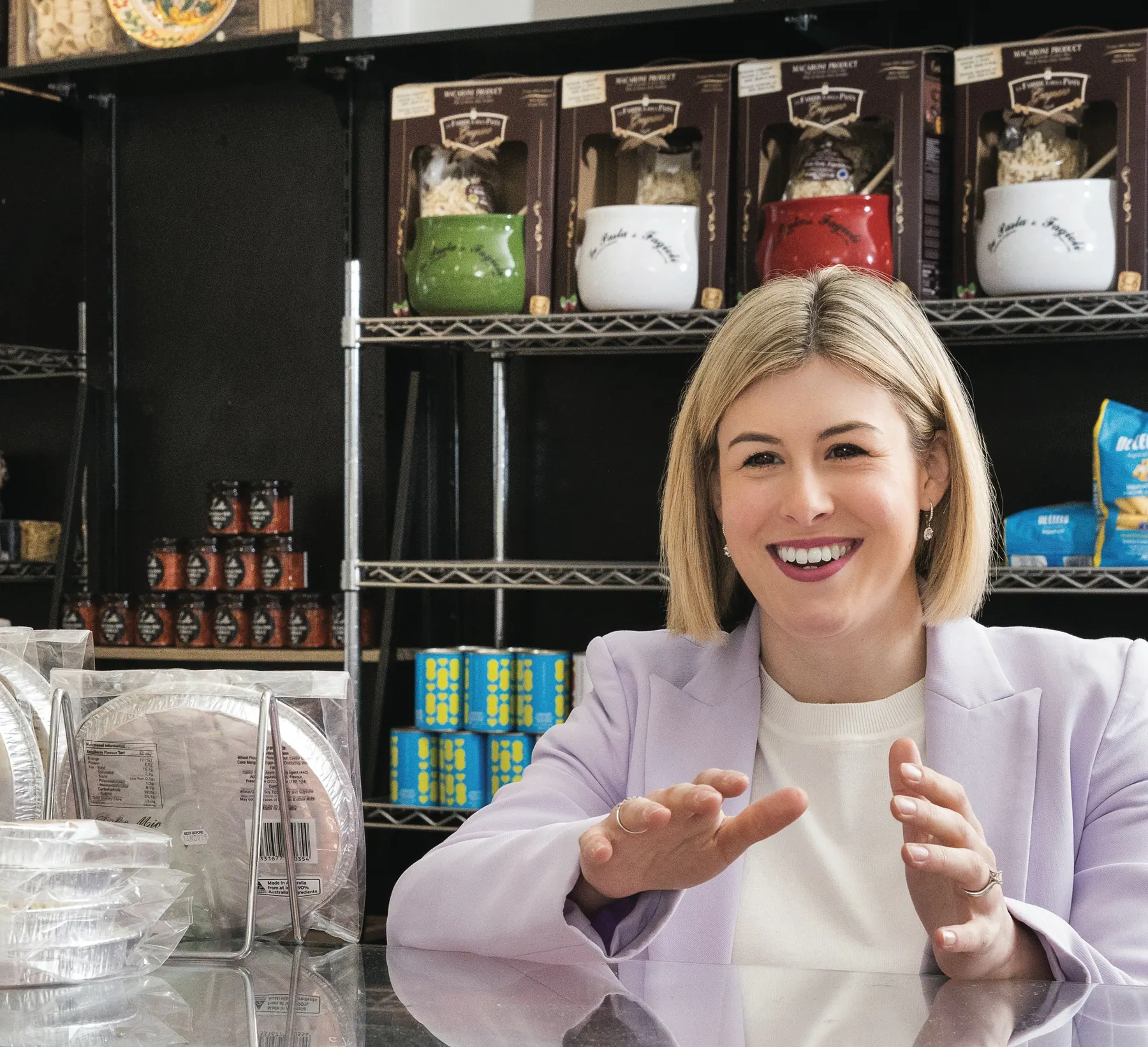 Jess Wilson smiling and talking with a shop owner across a deli counter