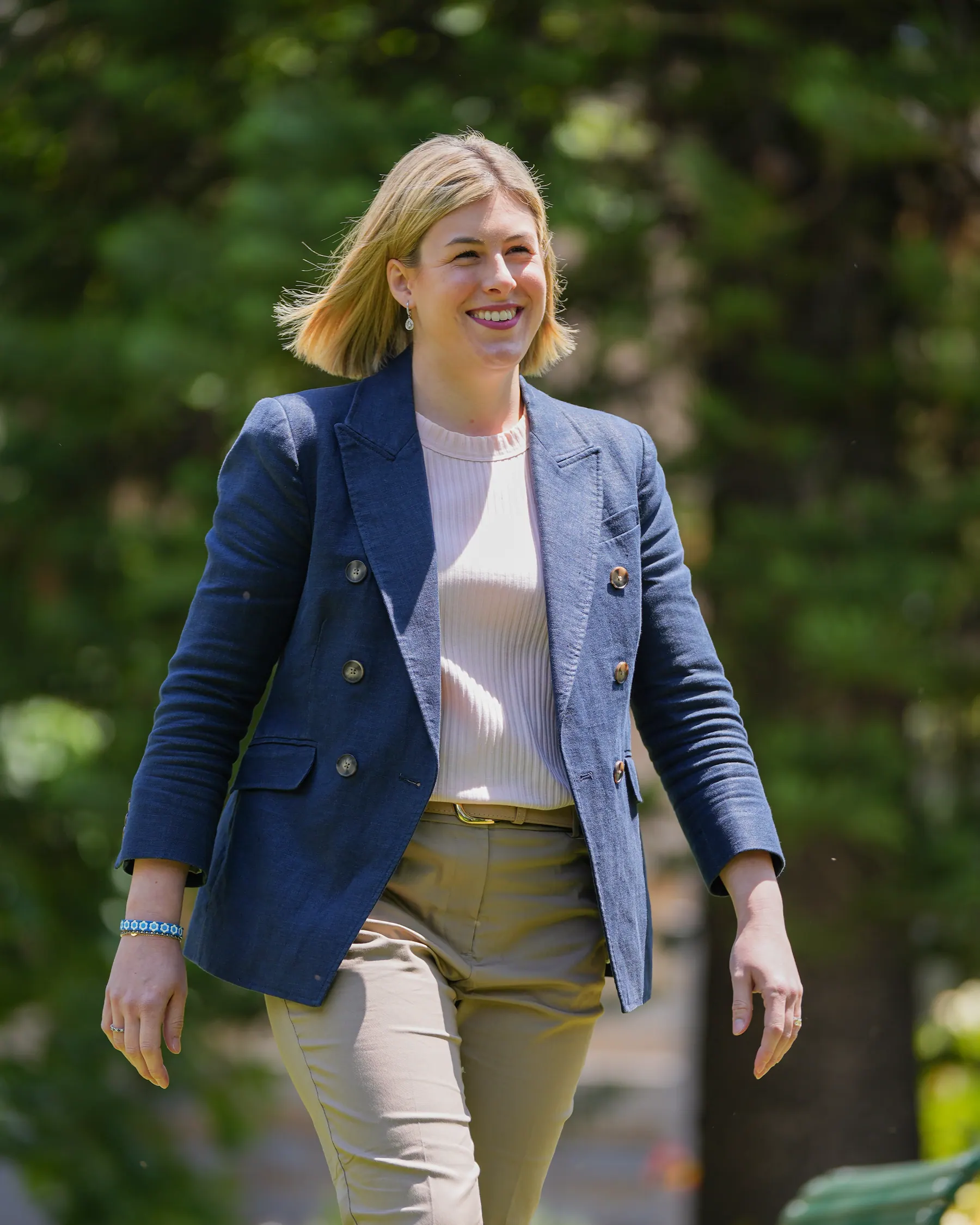 Jess Wilson walking through a park in a navy blazer